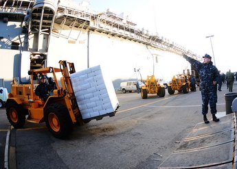 Sailors aboard the multipurpose amphibious assault ship USS Bataan (LHD 5) offload supplies in the ship's hangar bay as Bataan prepares to depart Naval Station Norfolk to provide humanitarian Assistance / Disaster Response in the aftermath of Haiti's devastating earthquake. (U.S. Army National Guard photo by Sgt. Steven C. Eaton, 65th Public Affairs Operations Center, Massachusetts National Guard/Public Domain)