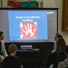 Den Jugendlichen wird eine Präsentation über aktuelle Zahlen von Kindern in Konflikten gezeigt. (Foto: RedTD/Klara Oppenheim)