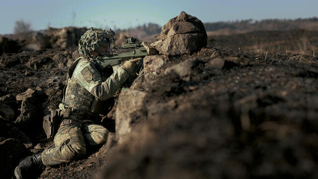 Ein Soldat ist in einer Stellung und zielt mit dem Sturmgewehr.