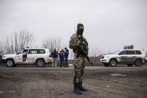 OSZE-Mitarbeiter (Hintergrund) der Special Monitoring Mission in der Ukraine überwachen Bewegungen von schweren Waffen in der Ostukraine.