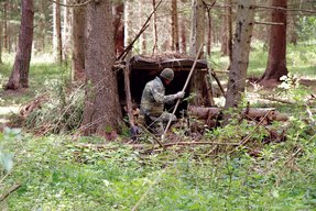 Eine getarnte Behelfsunterkunft aus Ästen und einer Plane zum Schutz vor Witterungseinflüssen. (Foto: Bundesheer)