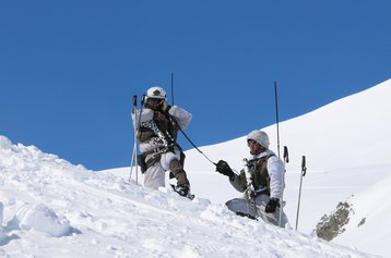 Ein Zugskommandant erteilt Befehle an seine Gruppenkommandanten an einem Übersichtspunkt hinter einer Geländekante über Funk. (Foto: RedTD/Gerold Keusch) 