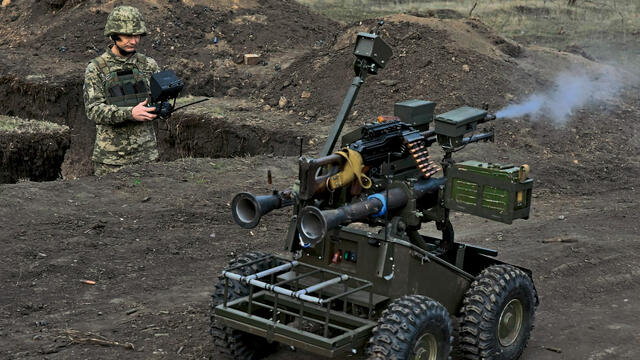 Ein unbemanntes System mit einem Maschinengewehr wird von einem Soldaten ferngesteuert.
