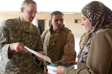 Ein US-Soldat übergibt Schulbücher an eine Lehrerin im Irak. (Foto: U.S. Army/Scott Schmidt; gemeinfrei)