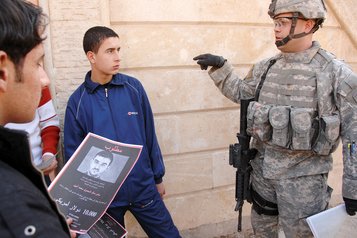 Ein Soldat eines Tactical PsyOps Teams unterhält sich mit irakischen Männern. (Foto: U.S. Army/Kieran Cuddihy; gemeinfrei)