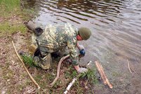 Szene der SERE-Ausbildung: Ein Kursteilnehmer schöpft Wasser aus einem Teich, das er danach filtern und abkochen wird. (Foto: Bundesheer)