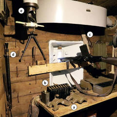 Kampfraum eines leichten Bunkers mit einem MG 26, den Abdeckungen für die Scharte (a), Magazinen (b), Begrenzung der Feuerbereiche mit Brettern (c), Reservelauf (d) und Periskop (e). (Foto: RedTD/Gerold Keusch)