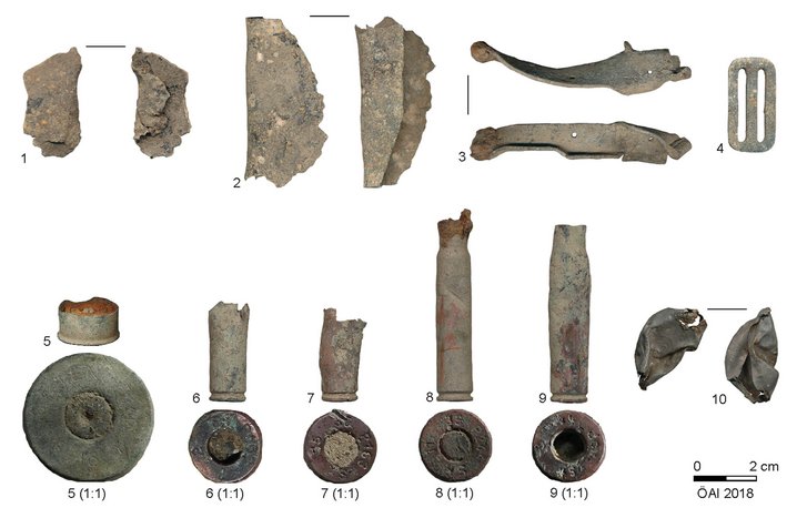 Auswahl an Funden der Metalldetektorprospektion: Granatsplitter mit Schmauchspuren (1 und 2), möglicher Wrackteil (3), Schnalle einer Gasmaske (4), Patronenhülse verschiedener Munitionsfabriken (5 bis 9), Bierkapsel der Schwechater Brauerei des Jahrganges 42 (10). (Foto: ÖAW/ÖAI).