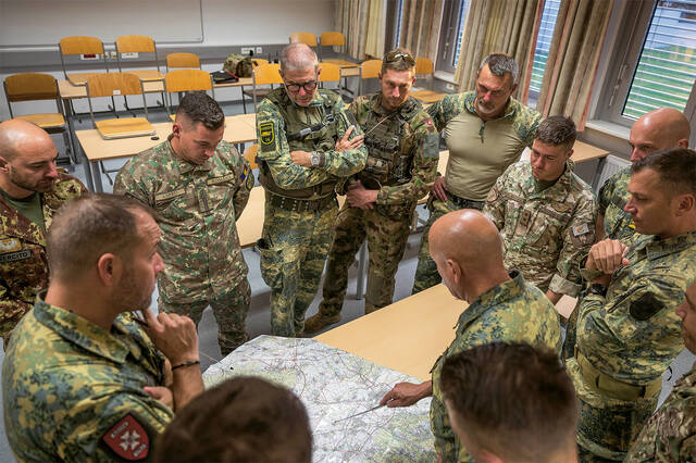 Nationale und internationale Führungstrainer besprechen an einer Lagekarte die Ausbildungsschritte des nächsten Tages. (Foto: Bundesheer/Paul Kulec)