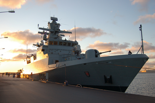 Die Korvette Braunschweig liegt während eines Sonnenunterganges im Hafen.