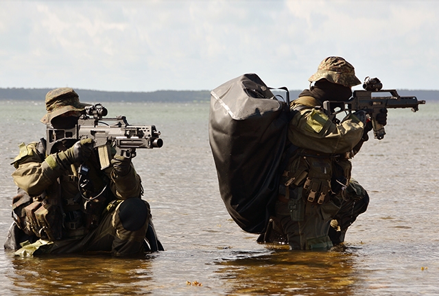 Zwei Kampfschwimmer stehen im Wasser vor dem Hafenbereich in Eckernförde und sichern die Umgebeung.