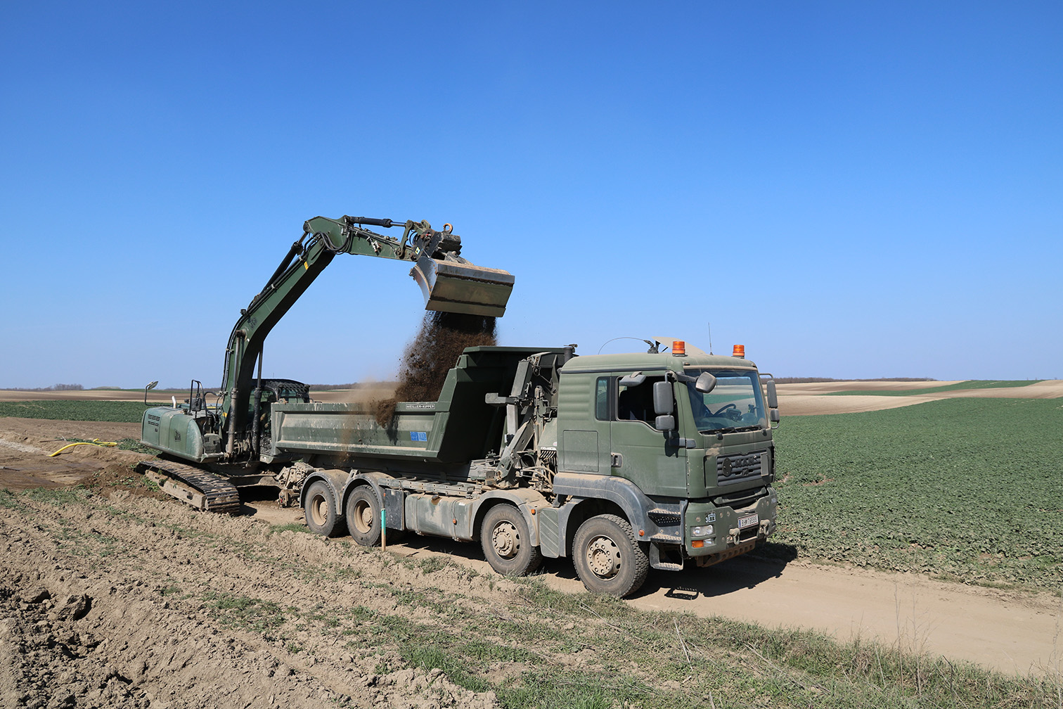 Ein JCB JS200LC-Bagger schaufelt überschüssige Erde auf einen MAN 41480 TGS-LKW mit Kipperaufbau. Beide Fahrzeuge stehen beim österreichischen Kontingent in Ungarn im Einsatz. (Foto: Gerold Keusch)